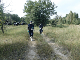 Zwei Mitarbeiter des BfS mit mobilen ODL-Messgeräten und Atemschutzmasken im Gelände (Bild anzeigen)